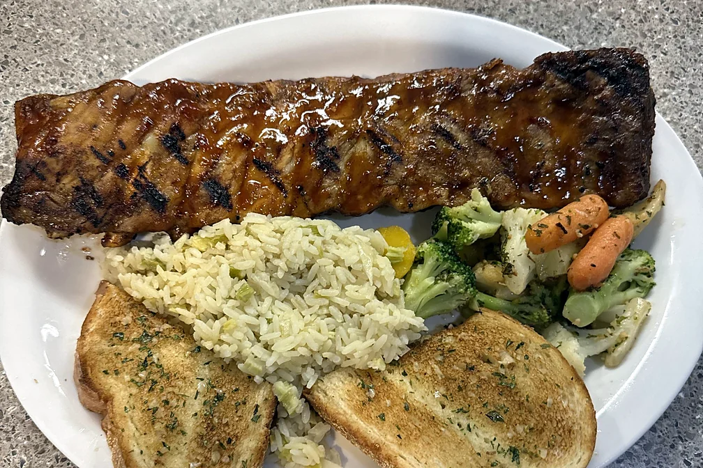 Full rack of BBQ back ribs with rice pilaf, vegetables and garlic toast